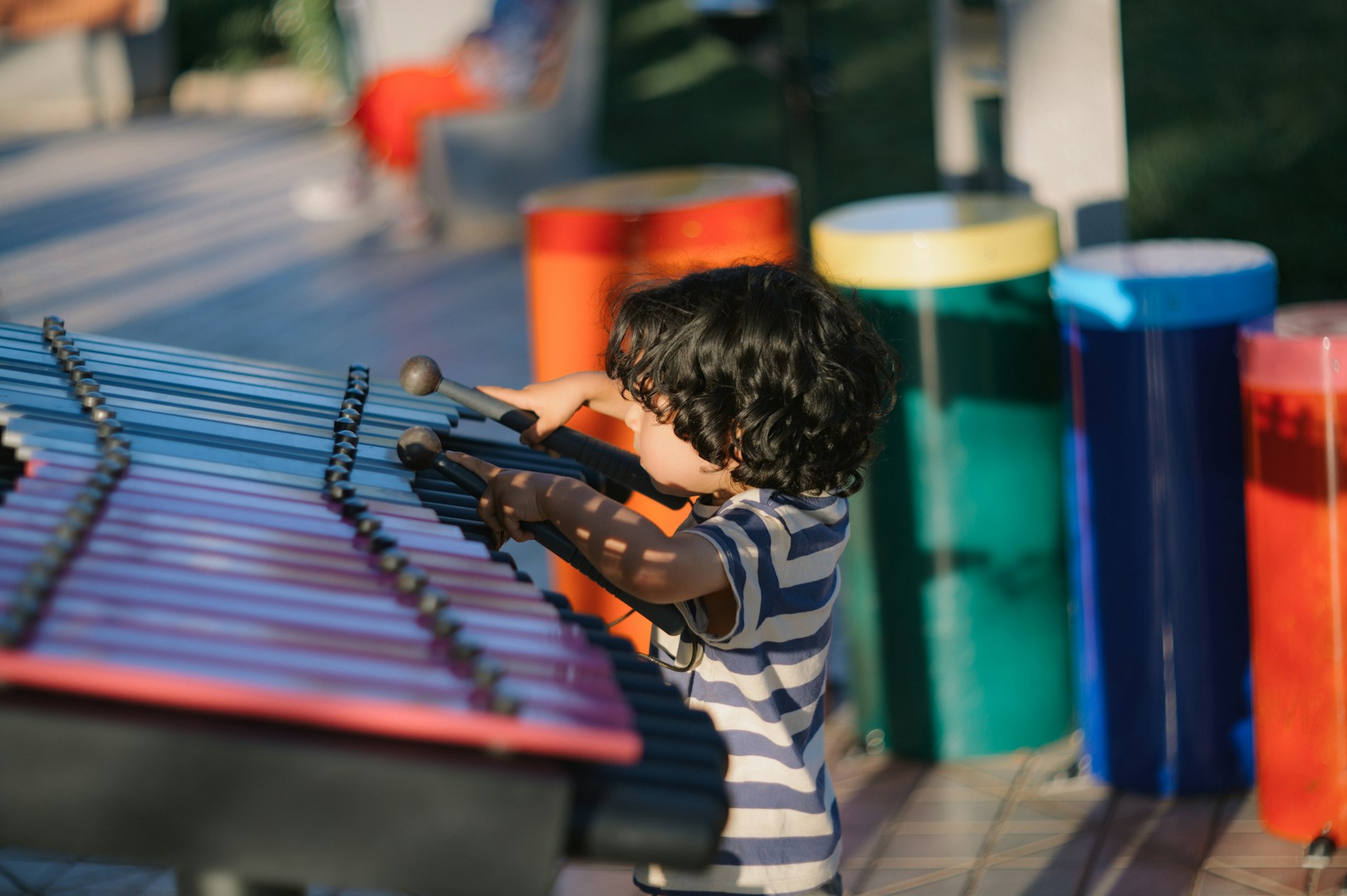 Child joyfully playing an outdoor xylophone